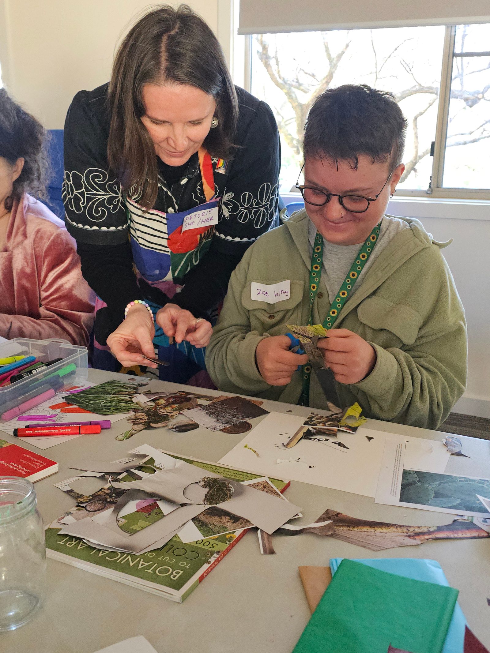An ACT Jubilant facilitator helping a participant with a collage at an art workshop