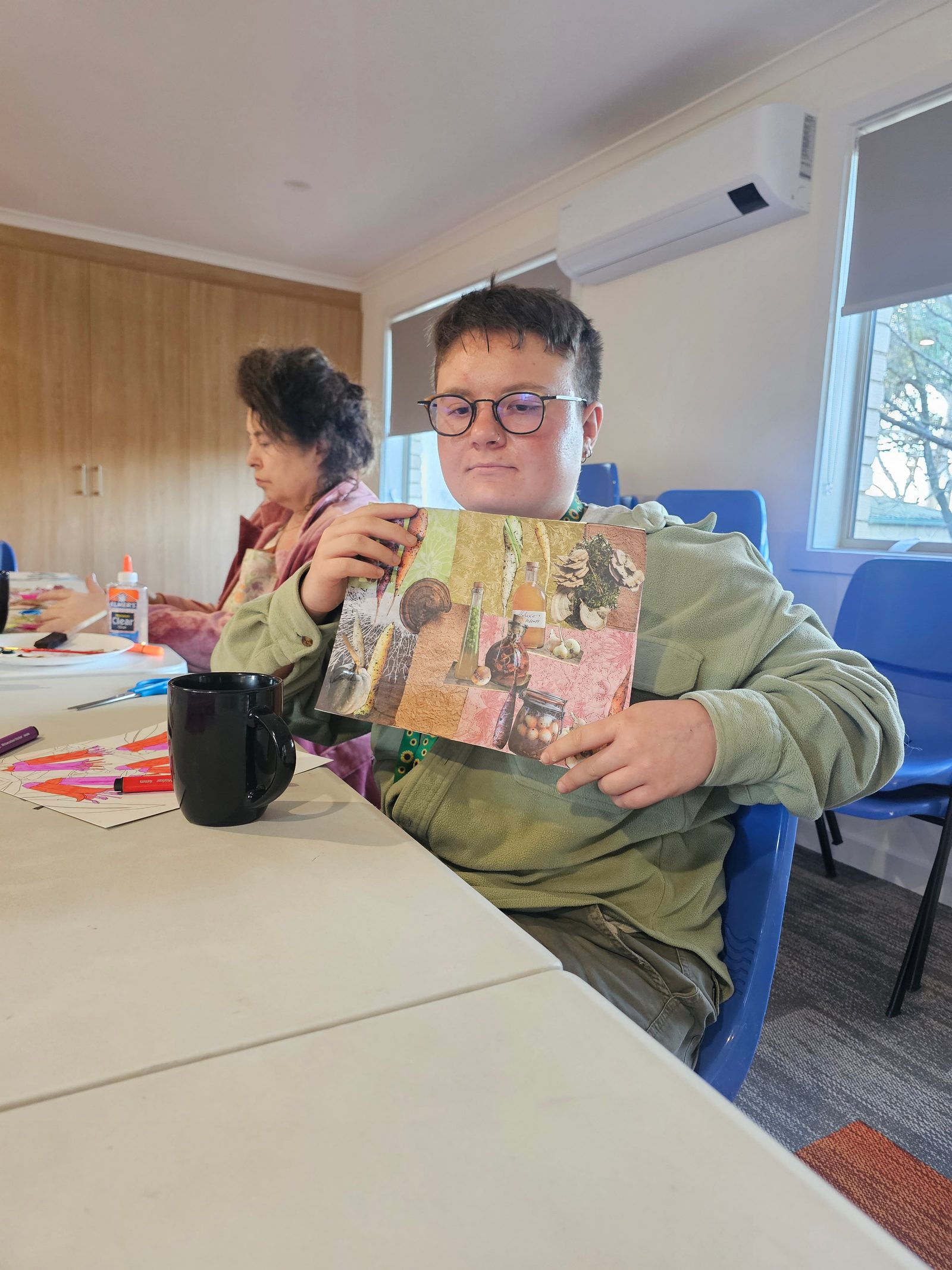 A participant proudly holding up a collage they created at an art workshop